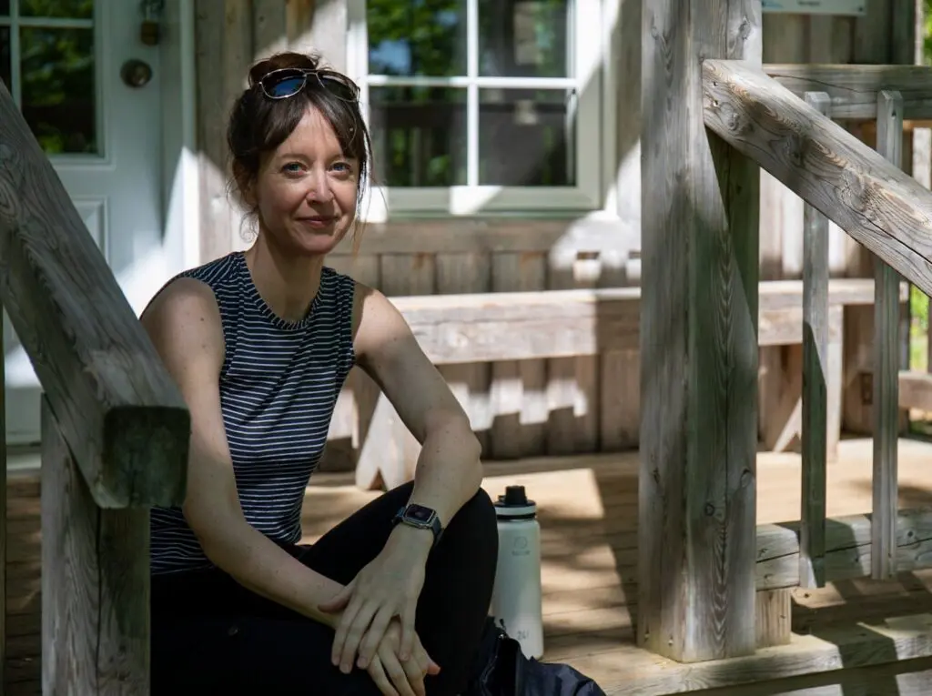 Krystyn Tully sitting on the porch of a refuge along a Quebec hiking trail.