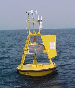 A yellow NOAA weather buoy bobs in the ocean. Image courtesy National Oceanic and Atmospheric Administration via Wikimedia Commons.